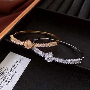Dettaglio macro di braccialetti a quadrifoglio in oro e argento con zirconi scintillanti