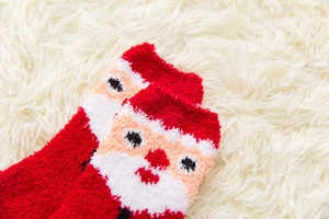Close-up of soft red coral fleece Christmas socks featuring a plush Santa Claus pattern