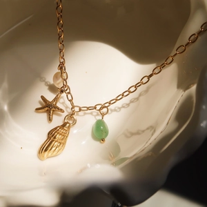 Close-up of golden ocean-themed necklace with starfish, shell and pearl charms