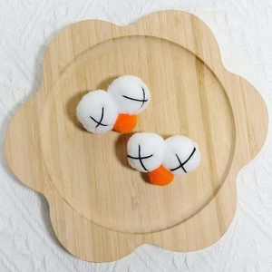 Détail d'accessoires de cheveux en peluche avec broderie yeux en croix sur plateau bambou