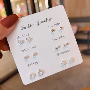 Detail of 6 pairs of silver stud earrings with pearls and bows for each day of the week