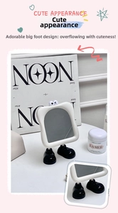 Detail showing cartoon eyes and wavy white frame of a cute foot-shaped desktop mirror