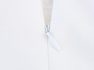Close-up of a white invisible zipper and textured chiffon fabric on a summer dress