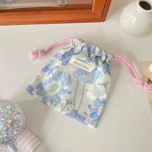 Dettaglio della custodia a coulisse con fiori blu e cordoncini intrecciati rosa