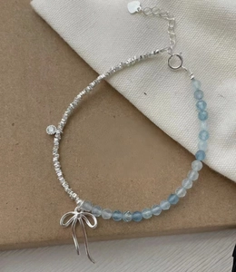 Detailed macro view of S925 beaded bracelet with blue gems and silver bow pendant