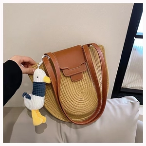 Detail of semi-circle woven cotton shoulder bag with leather strap and cute duck charm
