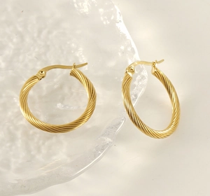 Detailed view of 18K gold-plated twisted cable hoop earrings on textured glass