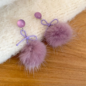 Dettaglio orecchini a fiocco viola con pompon di peluche e perle occhio di gatto