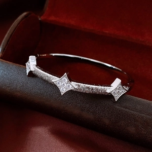 Macro shot of silver-tone textured bangle featuring three sparkling starburst motifs