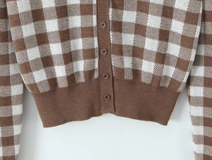 Detailed close-up of brown checkerboard knit cardigan with round buttons and ribbed hem