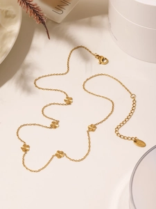 Detail of 18K gold-plated clover necklace featuring sunburst texture and s.steel tag