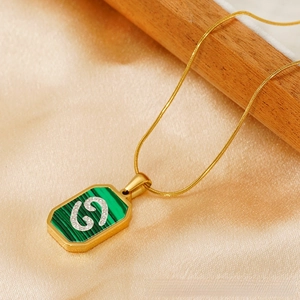 Macro detail of gold Cancer zodiac necklace with malachite inlay and sparkling crystals