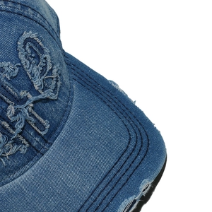 Close-up of distressed denim baseball cap showing parallel stitching and embroidery