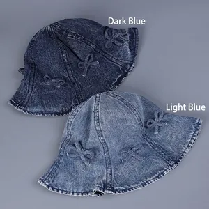 Vue à plat de bobs en jean avec nœuds décoratifs en bleu foncé et bleu clair