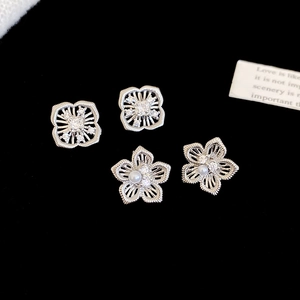 Makroaufnahme von silbernen Blumenohrringen mit Perlen und Zirkonia auf schwarzem Samt
