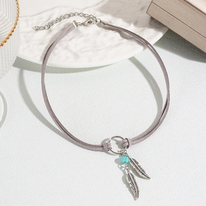 Detail of bohemian necklace with silver feather charms and turquoise bead on grey cord