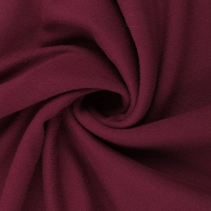 Detailed macro view of soft burgundy ribbed knit fabric texture with elegant swirl pattern