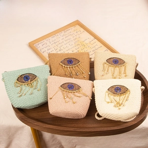 Detailed close-up of colorful straw woven bags for kids featuring beaded evil eye charms
