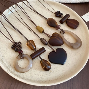 Detail view of vintage resin pendant necklaces in earth tones on a ceramic tray