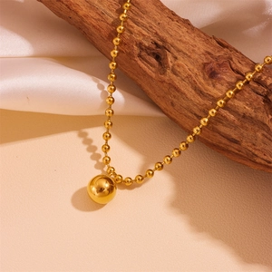 Gold stainless steel beaded chain necklace with spherical pendant on wooden background