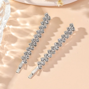 Elegant pair of silver rhinestone hair clips for wedding hairstyles on a beige background