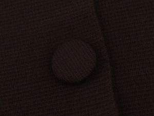 Vue macro du cardigan en tricot chocolat avec un bouton recouvert de tissu assorti