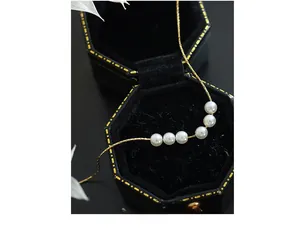 Detailed view of five white pearls on a gold-plated titanium steel square chain necklace