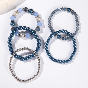 Dettaglio macro del set di cinque braccialetti multistrato con cristalli blu e perle finte