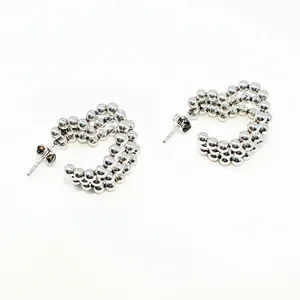 Detailed macro view of silver beaded C-shaped stainless steel earrings with metallic luster