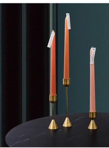 Close-up of golden metal candle holders with scented candles on a black marble table