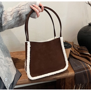 Close-up of brown suede shoulder bag with plush shearling trim and long handle