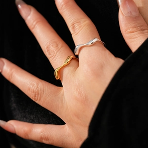 Close-up of elegant gold and silver wavy irregular rings on finger with soft lighting