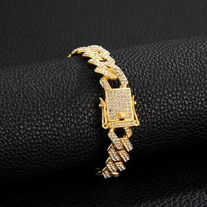 Detail of gold iced-out Cuban link bracelet on black leather roll with square safety clasp