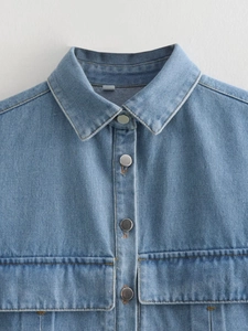 Détail d'une chemise en jean bleu clair avec col classique et boutons métalliques argentés