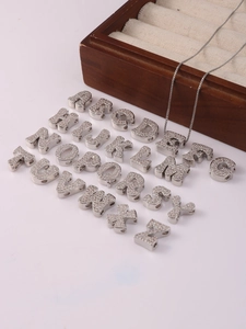 Macro shot of a set of 26 silver A-Z alphabet pendants with inlaid clear cubic zirconia