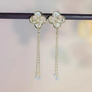 Detail of floral butterfly tassel earrings with gold finish and white pearl beads