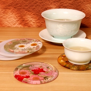 Detailed view of round resin coaster with real dried flowers on a wooden table setup