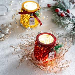 Christmas mercury glass candle holders with pine cones and red bows on snow background