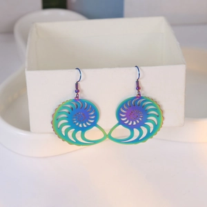 Macro shot of iridescent nautilus shell hollow-out earrings on a jewelry box edge