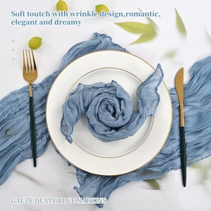 Detailed close-up of a dusty blue gauze napkin folded into a rose on a gold rimmed plate