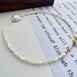 Detail of baroque freshwater pearl necklace with white beads and golden lobster clasp