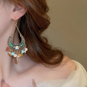 Detail of bohemian moon-shaped earrings with colorful beads and sequins on a model