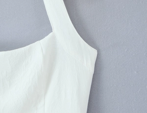 Detailansicht eines weißen rückenfreien Kleides mit Crinkle-Textur und Neckholder-Ausschnitt