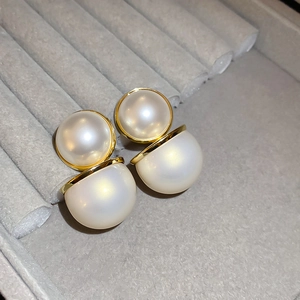 Vue détaillée de boucles d'oreilles doubles perles rouges et blanches sur plateau velours