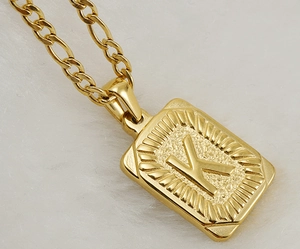 Vue macro d'un pendentif rectangulaire en acier doré avec gravure de la lettre K