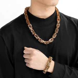Close-up of a man wearing a thick gold Byzantine chain necklace and bracelet set