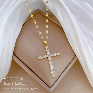 Macro shot of gold-plated titanium cross pendant with sparkling stones on silk fabric