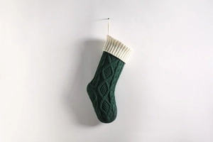Close-up of chunky cable knit Christmas stocking in dark green with creamy white cuff