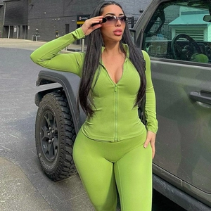 Detail of green long-sleeve zip-up sports jacket and tight leggings set outdoors