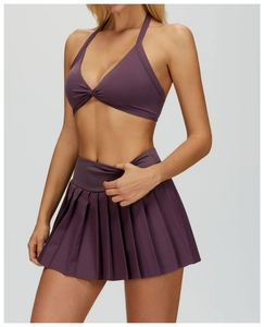 Detail of deep purple halter yoga bra with knot design and high-waist pleated skirt set
